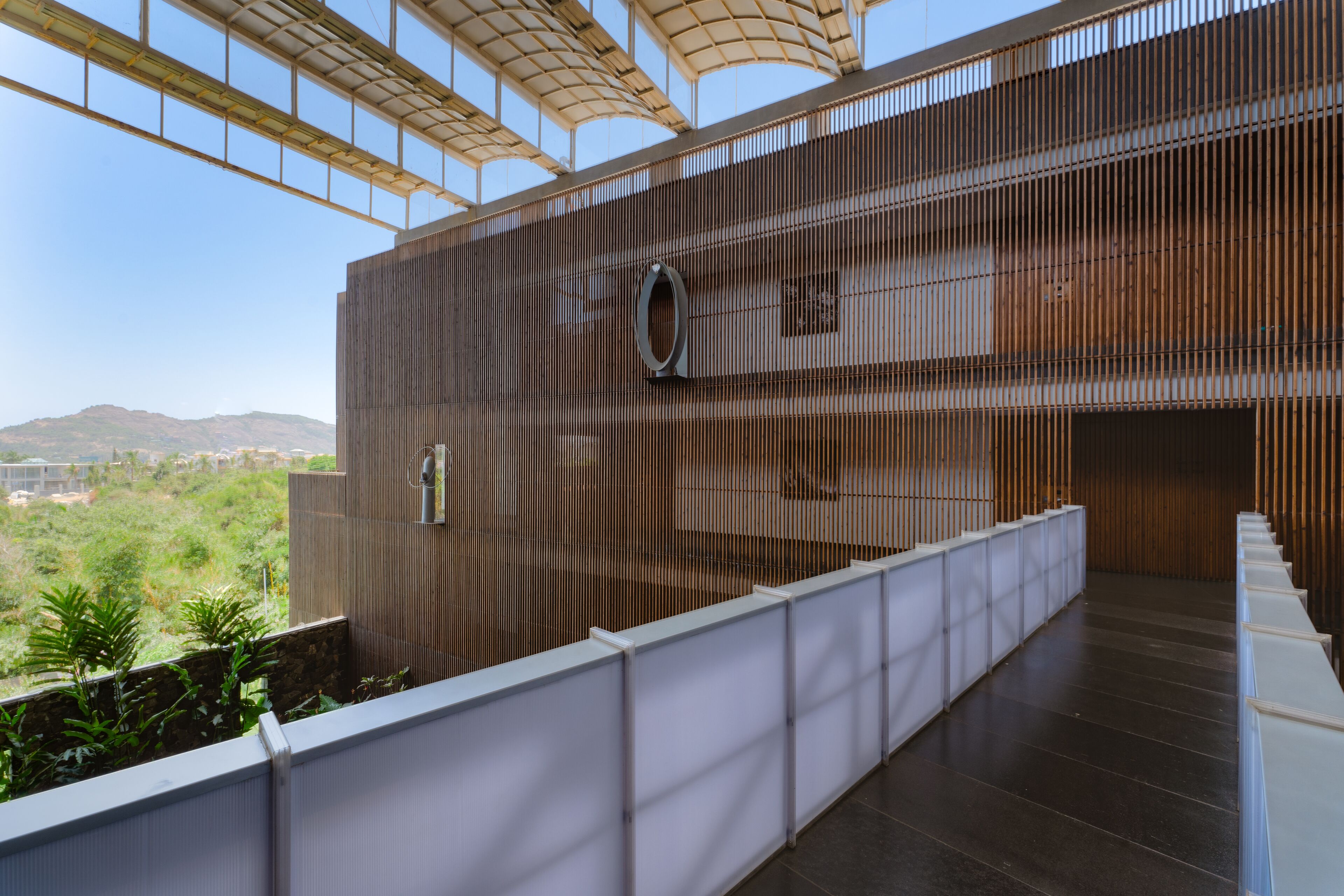 A modern building with a glass ceiling, a staircase, and a view of greenery and hills.