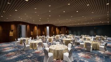 A large conference room with round tables, white chairs, and a patterned carpet.