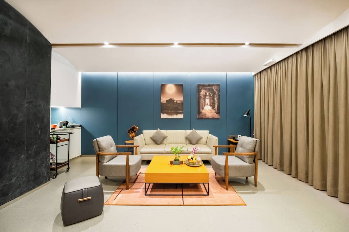 A modern living room with a sofa, two armchairs, a coffee table, and artwork on the wall.