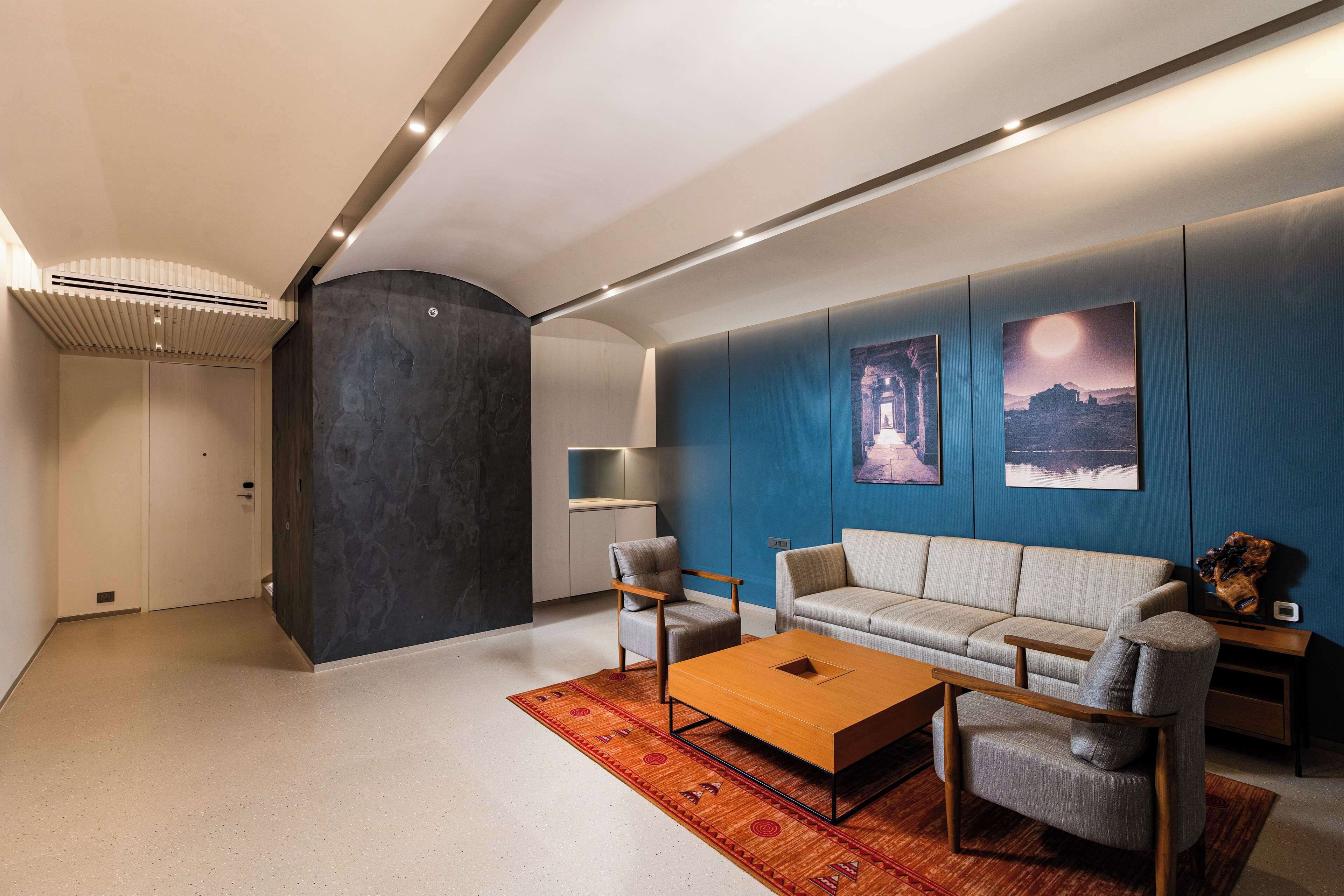 A modern living room with a sofa, armchairs, a coffee table, and artwork on the wall.