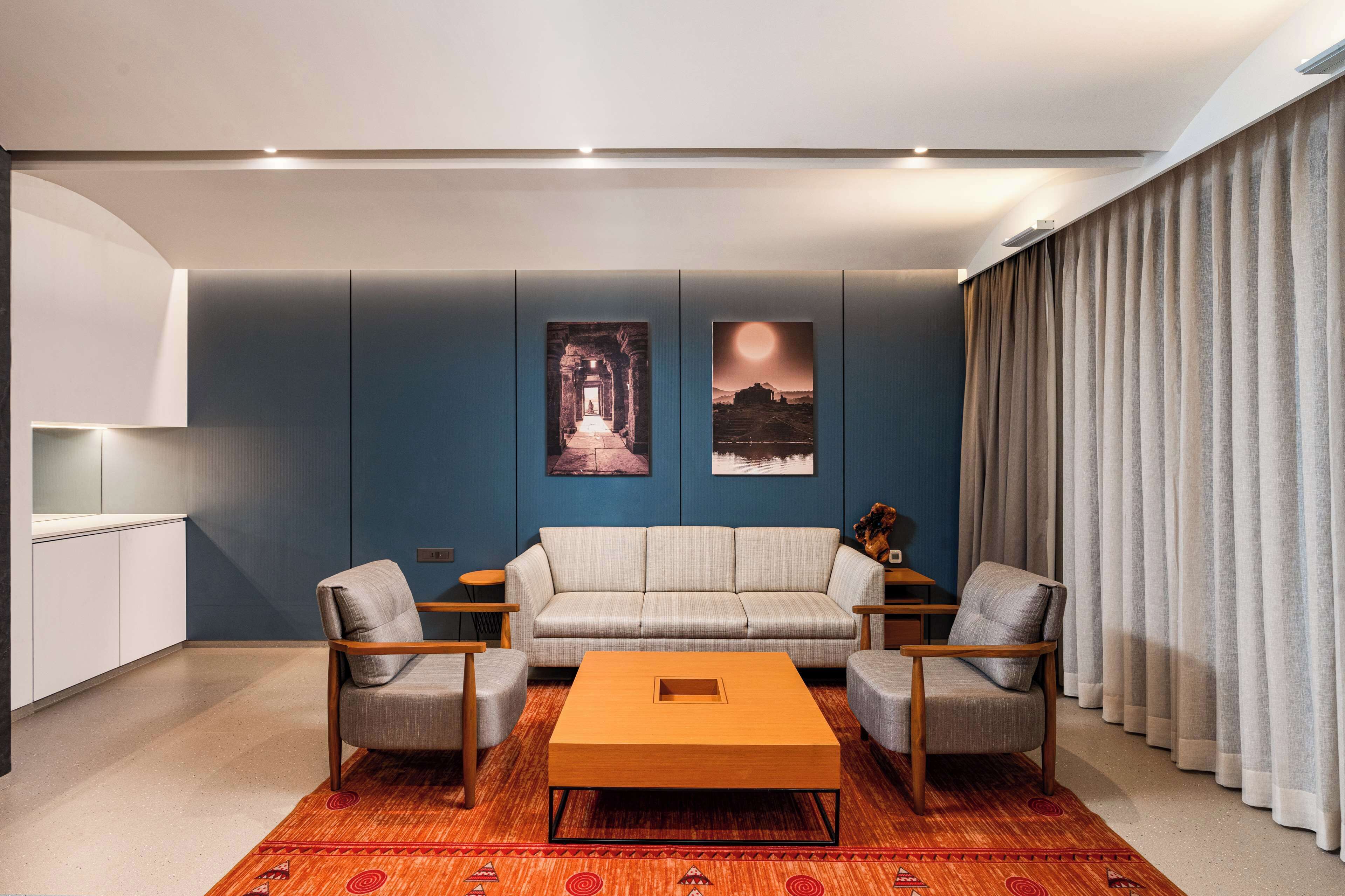 Una sala de estar moderna con un sofá, dos sillones, una mesita de centro y obras de arte en la pared.