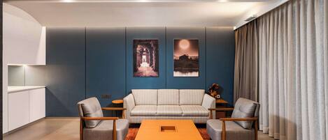 Una sala de estar moderna con un sofá, dos sillones, una mesita de centro y obras de arte en la pared.