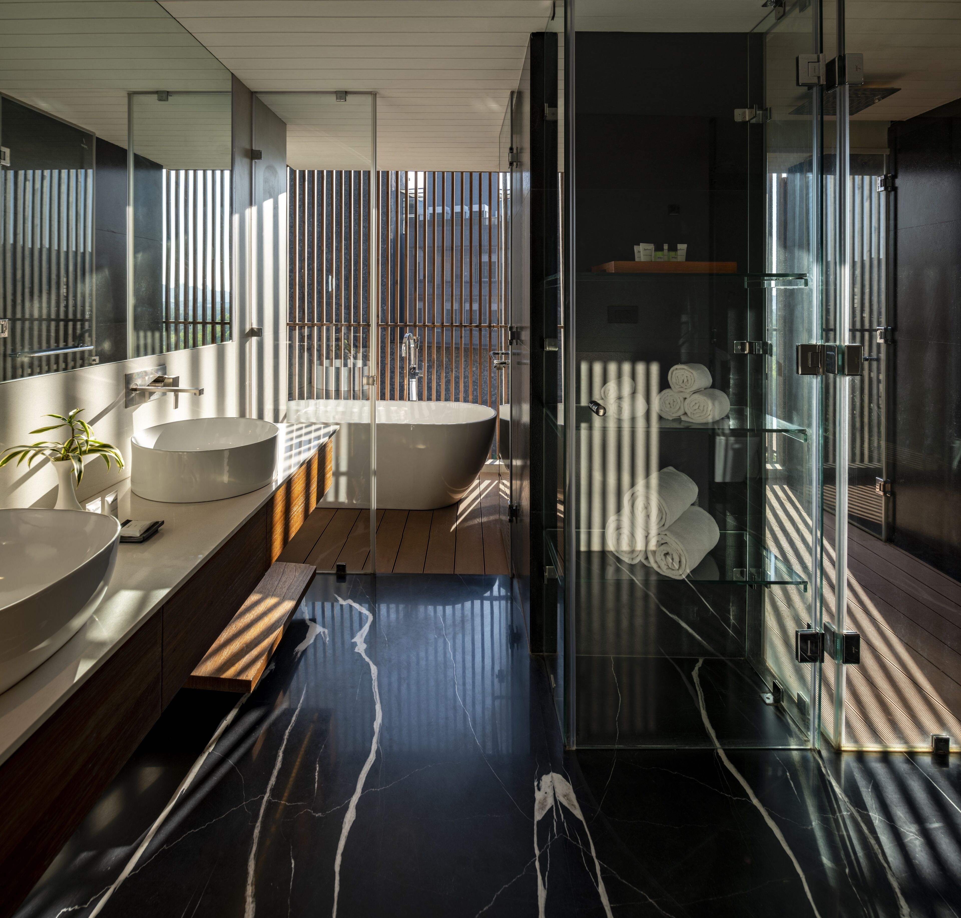 Un baño moderno con un espejo grande, una bañera, una ducha con cerramiento de vidrio y un tocador de madera.
