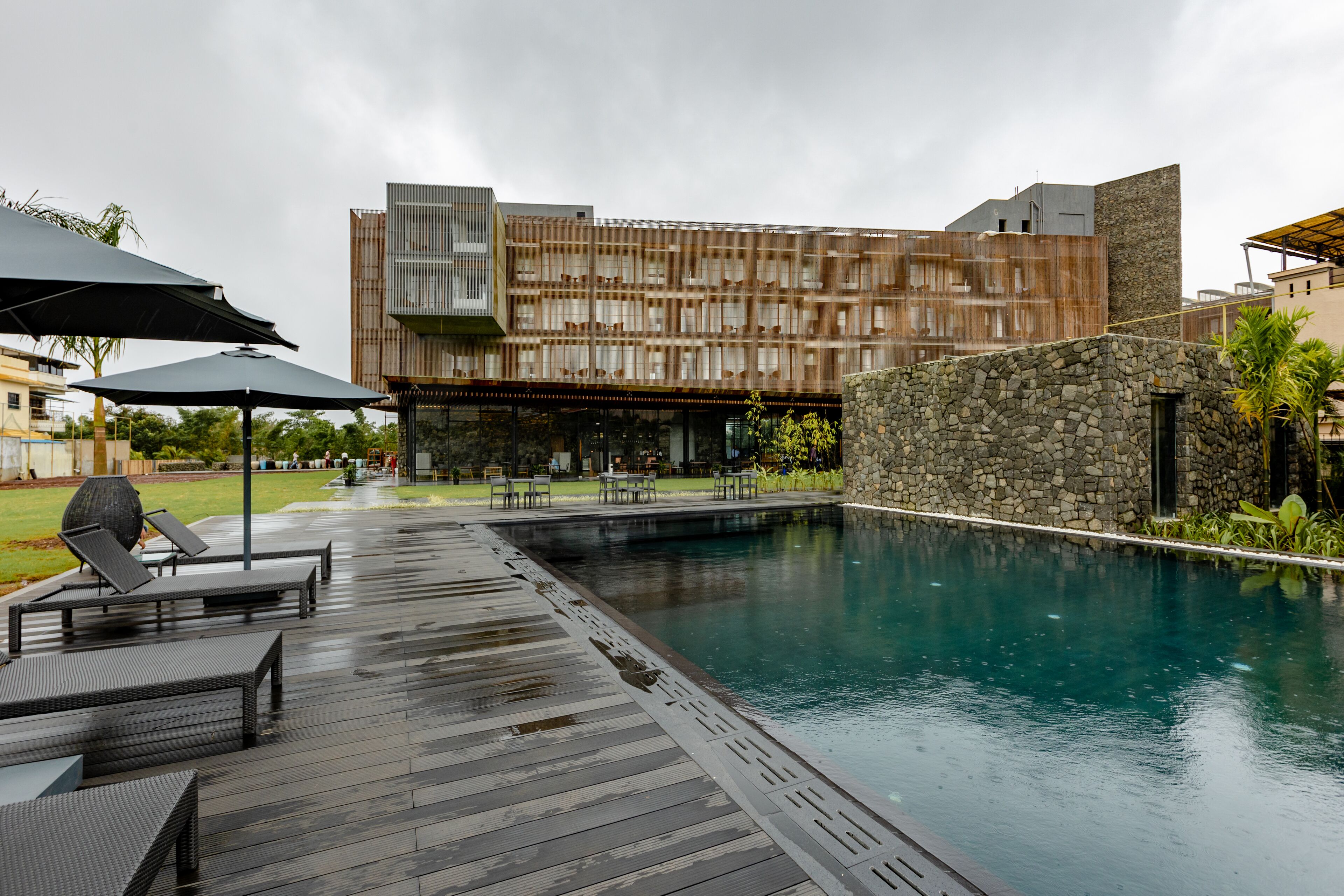 Un hotel moderno con piscina, mobiliario exterior y una pared de piedra.