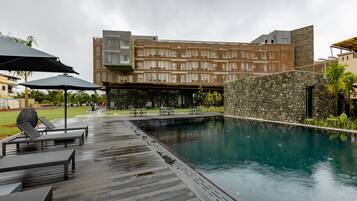 Un hotel moderno con piscina, mobiliario exterior y una pared de piedra.