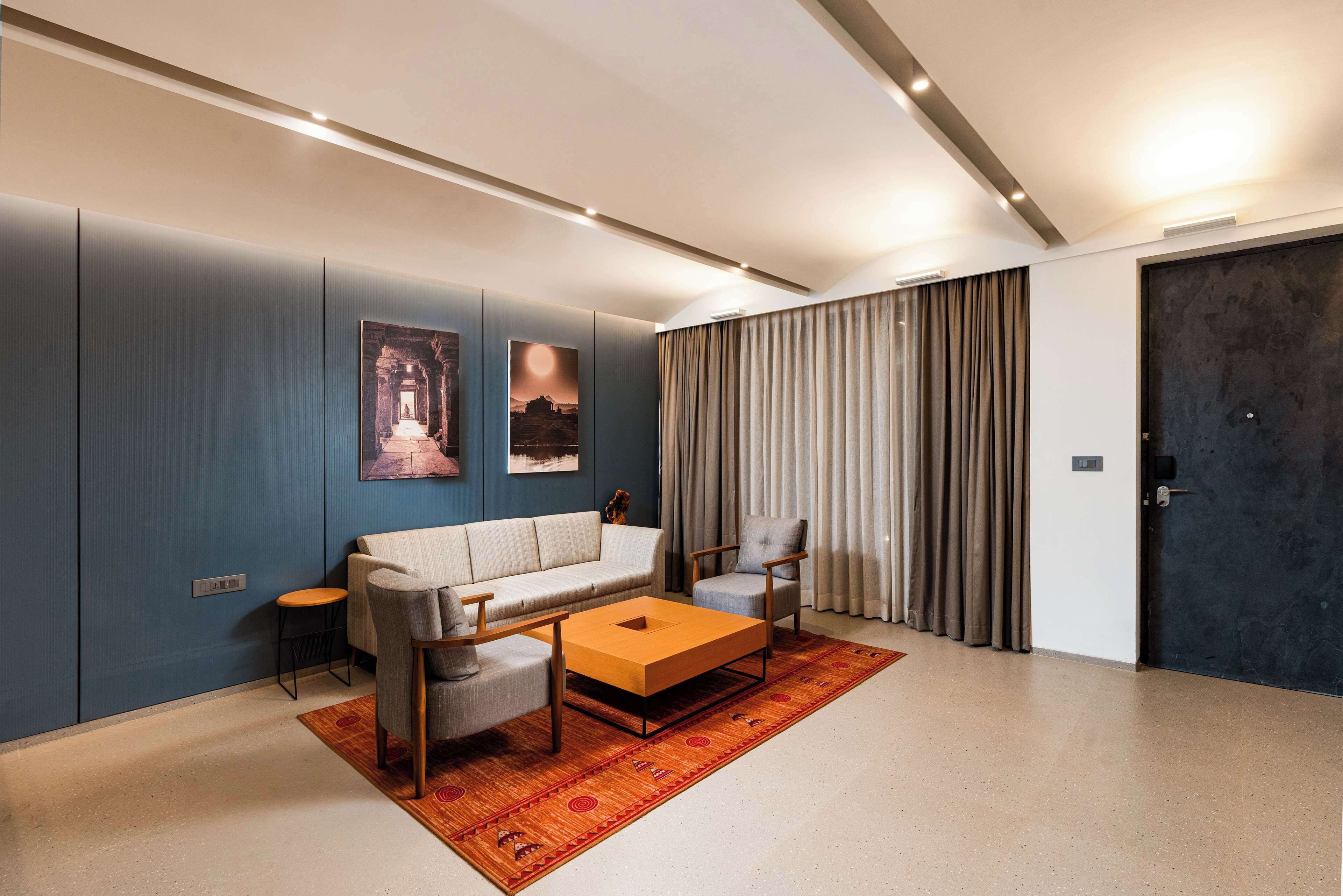 A modern living room with a sofa, two armchairs, a coffee table, and a rug.