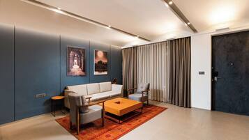 A modern living room with a sofa, two armchairs, a coffee table, and a rug.