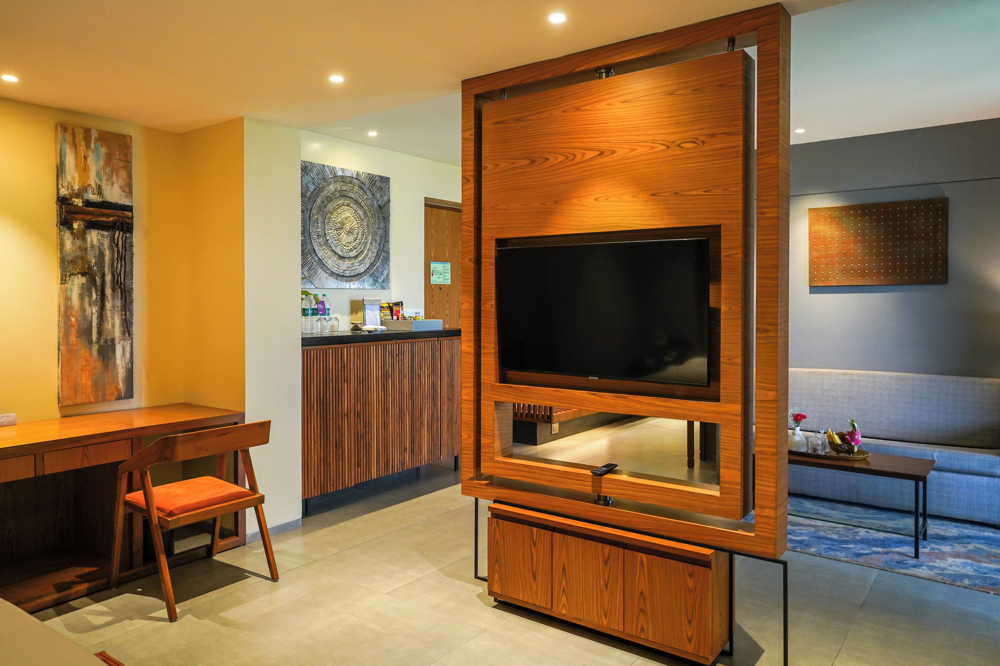 Een moderne woonkamer met een grote flatscreen televisie, houten meubels en kunstwerken aan de wand.