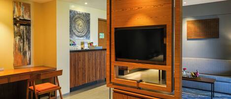 A modern living room with a large flat-screen TV, wooden furniture, and artwork on the walls.