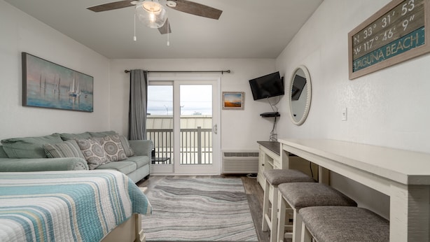 A bedroom with a bed, a ceiling fan, a TV, a desk, and a view of the outside. - New Listing!  Modern studio ocean block with a pool (Ocean City)