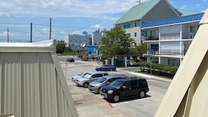 A parking lot with several cars, a building with a green roof, and a clear blue sky with clouds. - New Listing!  Modern studio ocean block with a pool (Ocean City)