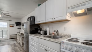 A modern kitchen with white cabinets, a stainless steel refrigerator, a stove, and a sink. - New Listing!  Modern studio ocean block with a pool (Ocean City)