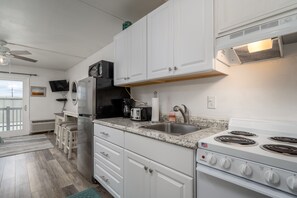 A modern kitchen with white cabinets, a stainless steel refrigerator, a stove, and a sink.