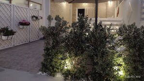 Une cour dotée d’un espace de repos abrité, de plantes en pot et d’un mur en pierre.