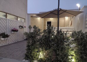 A courtyard with a covered seating area, potted plants, and a stone wall. - Vacation home from Elisa (Marsala)
