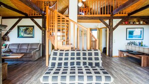 Amplia sala de estar con escalera de madera, un sofá y un banco.