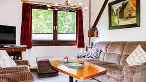 Una sala de estar acogedora con un sofá, una mesa de centro de madera y un televisor.