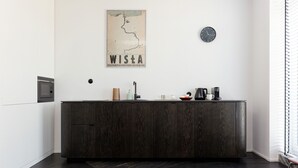 Une cuisine moderne avec des meubles de couleur bois foncé, un four à micro-ondes, un évier et une horloge au mur.
