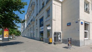 Une rue bordée d’immeubles, une enseigne indiquant un « Notariusz » et un magasin appelé « Rainbow ».