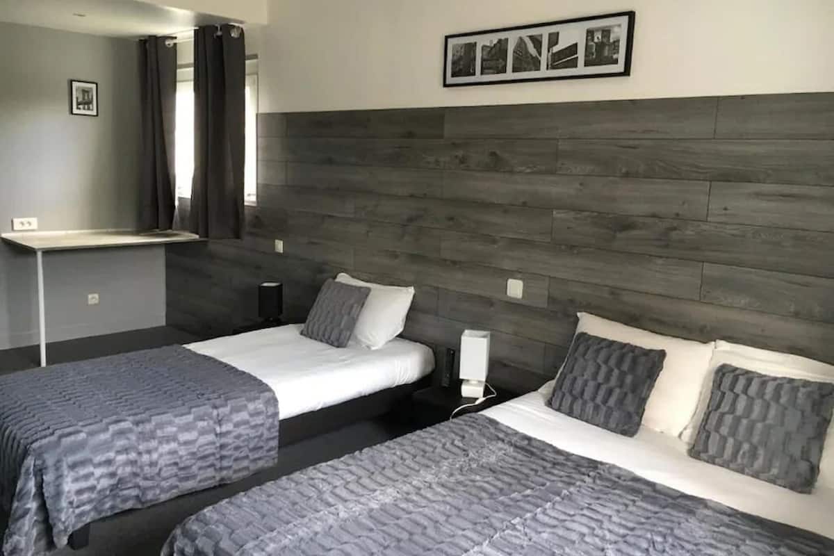 A hotel room with two beds, a desk, and a mirror.