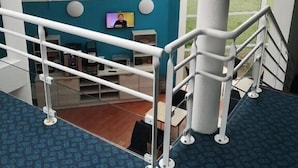 A staircase with a blue patterned carpet, white handrails, and a view of a room with a teal accent wall, a television, and a desk. - Hotel Mervil Airport (Merville)