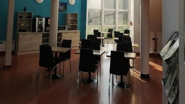 A spacious indoor area with a high ceiling, a mezzanine level, and large windows allowing natural light. - Hotel Mervil Airport (Merville)