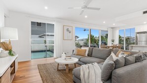 A modern living room with a grey sofa, a coffee table, and a pool view. - Sunrise Mansion with Pool - 6 bedrooms (KINGSCLIFF)