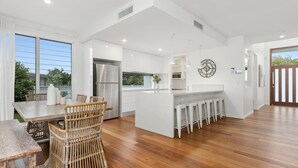 A modern kitchen with a central island, white cabinetry, and a stainless steel refrigerator. - Sunrise Mansion with Pool - 6 bedrooms (KINGSCLIFF)