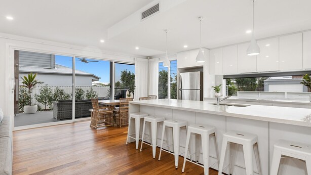 A modern kitchen with a large island, bar stools, and a view of the backyard. - Sunrise Mansion with Pool - 6 bedrooms (KINGSCLIFF)