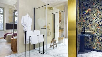 Ein modernes Badezimmer mit Duschkabine aus Glas, Marmorboden und einer Wand mit tropischem Dekor.