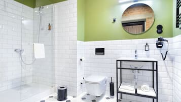 A bathroom with a glass shower enclosure, a white toilet, a sink with a black frame, and a mirror on the wall.