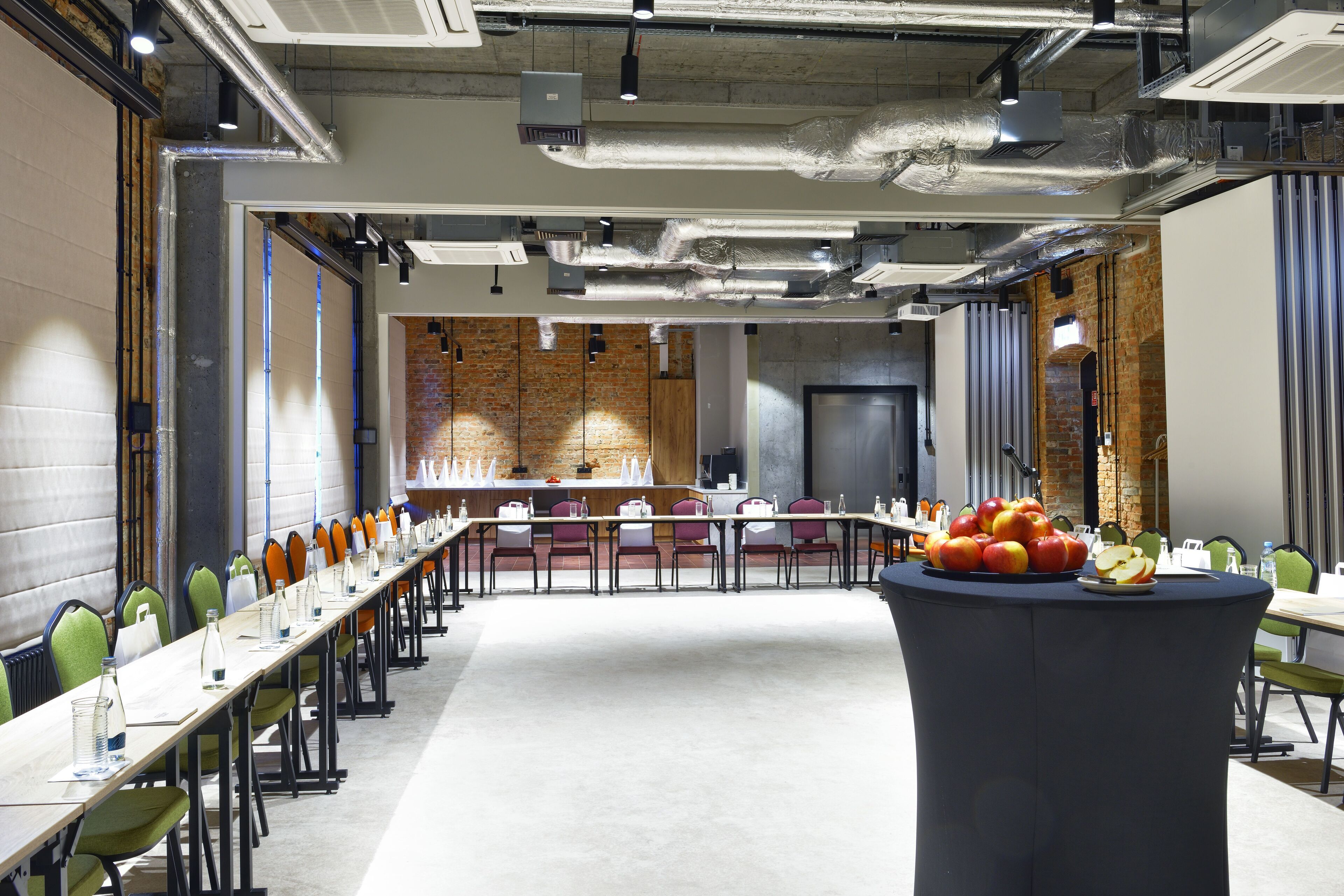 Un salón de conferencias con una larga mesa, sillas y una exposición de frutas.
