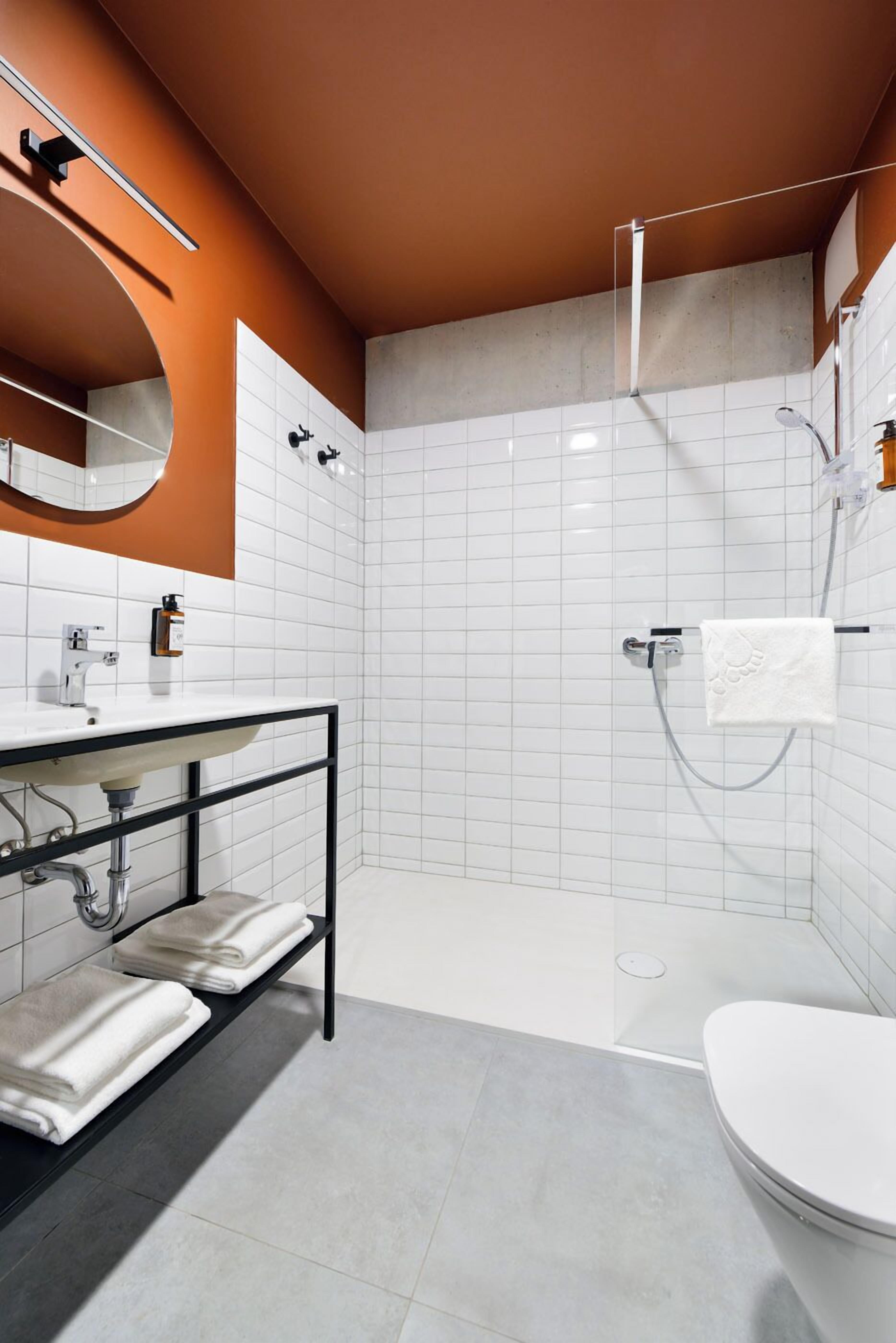 Un baño moderno con lavamanos blanco, encimera negra y cabina de ducha con mampara de vidrio.