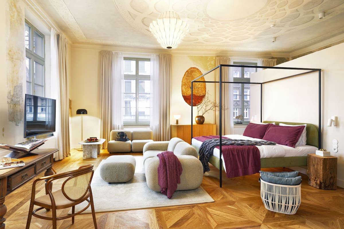 Quarto moderno com uma cama grande, uma escrivaninha com computador, uma cadeira e um sofá.