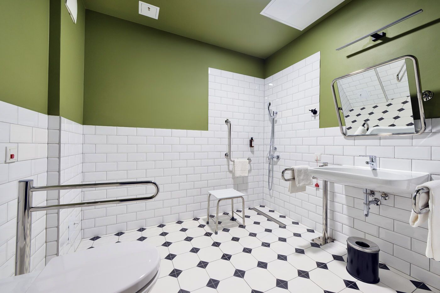 Ein Badezimmer mit weißen und schwarzen sechseckigen Fliesen, einer weißen Toilette, einem Waschbecken mit Spiegel und einer Duschkabine.