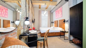 Una habitación de hotel moderna con paredes de ladrillo visto, una cama estilo loft, un escritorio con silla y un armario amplio.
