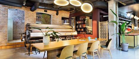 A modern dining area with a long wooden table, four chairs, and a piano in the background.