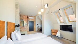 Una camera d'albergo moderna con un letto grande, una scrivania, una sedia e una TV a parete.
