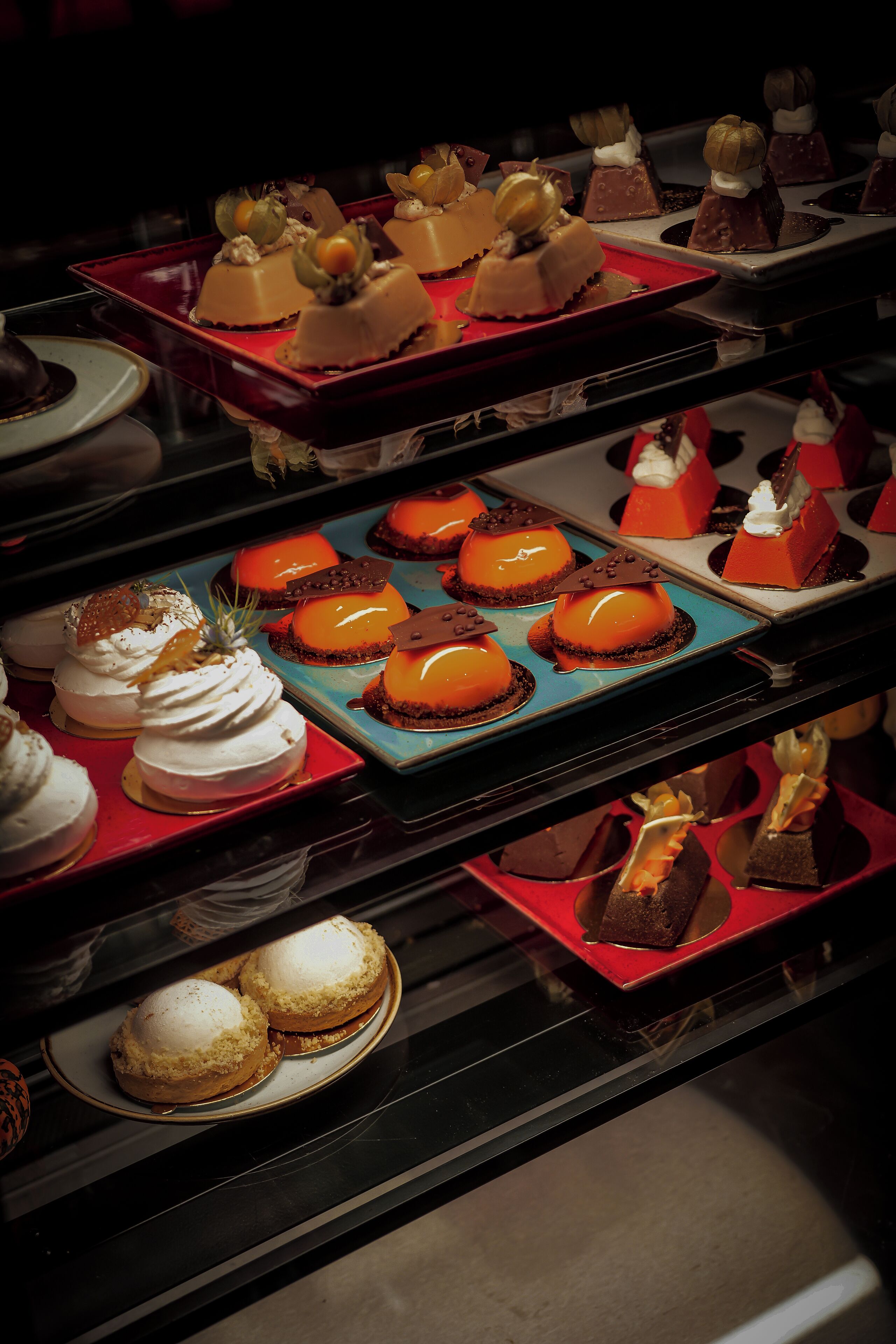 A variety of desserts on display in a well-lit area, likely a dessert counter or buffet section of a hotel.