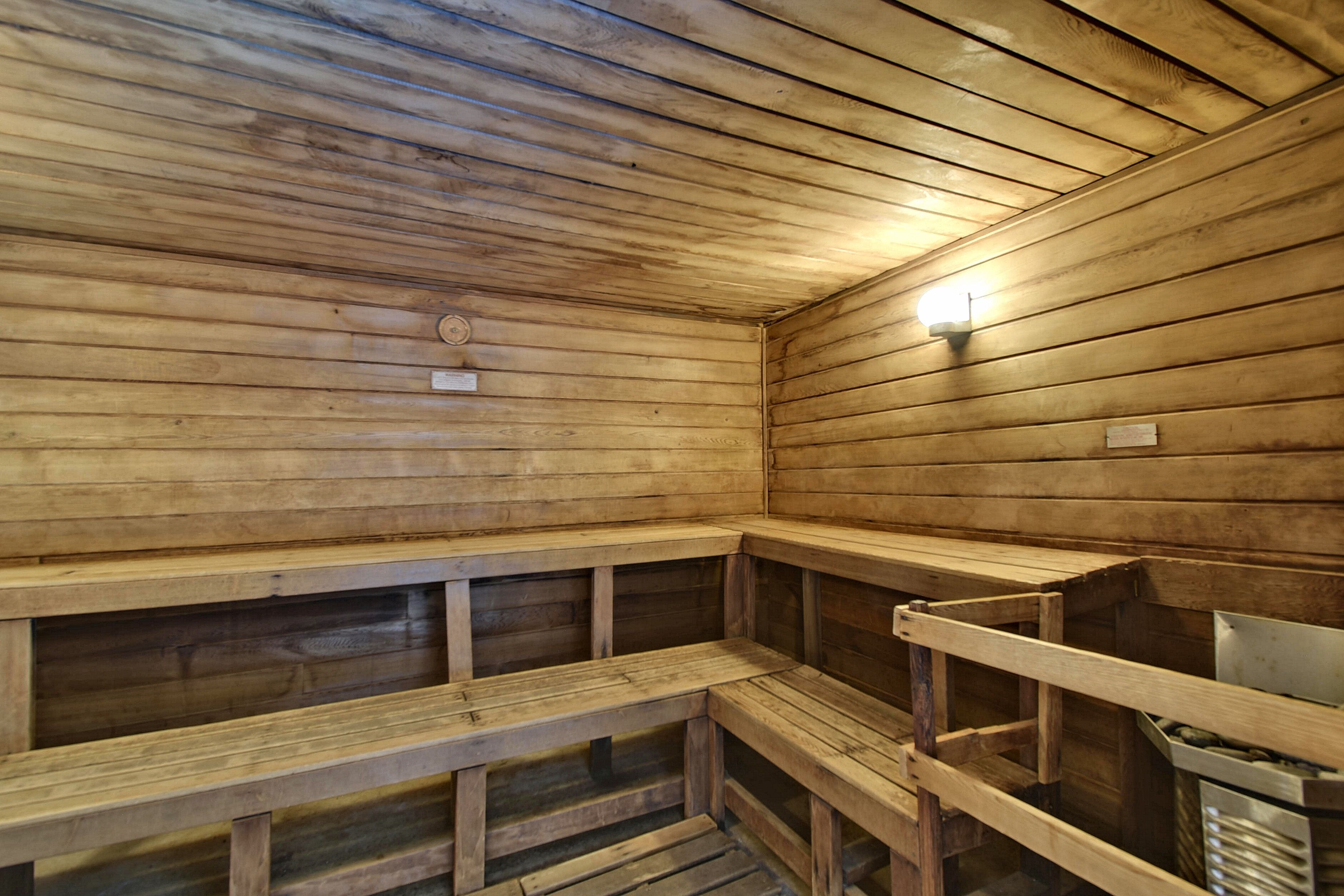Een sauna met houten banken en wanden, een bank op de voorgrond, en een lamp aan de muur.