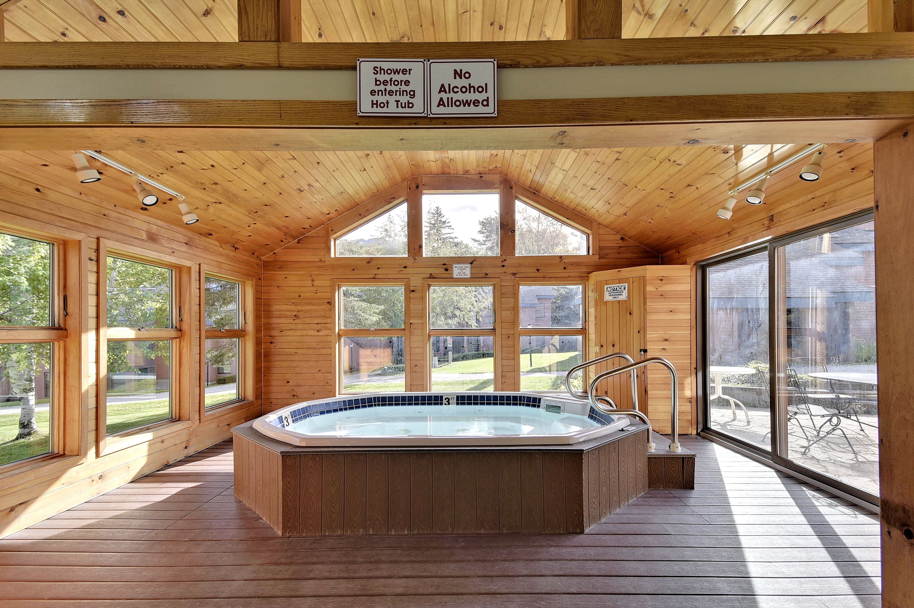 Una cabaña de madera con jacuzzi, ventanas amplias y un cartel que prohíbe el consumo de alcohol.