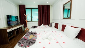 Habitación de hotel con cama, televisión, escritorio y ventana con cortinas.
