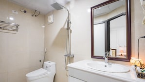 Un baño con inodoro, lavamanos, espejo y ducha.