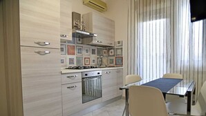 A modern kitchen with a built-in oven, a gas stove, and a dining area with a table and chairs. - Casa Vacanze le Palme Netine (Noto)