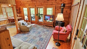 Un intérieur de chalet chaleureux avec une cheminée, un téléviseur et un coin repas.