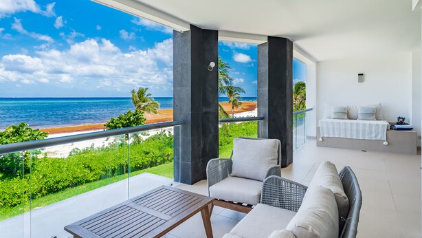 A balcony with a view of the beach and ocean, furnished with a table, chairs, and a sofa. - Casa Shell, Where the Caribbean Is Part of the View (Playa del Carmen)