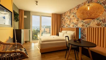 Een moderne hotelkamer met een groot bed, een eettafel, een rieten stoel en uitzicht op de stad.