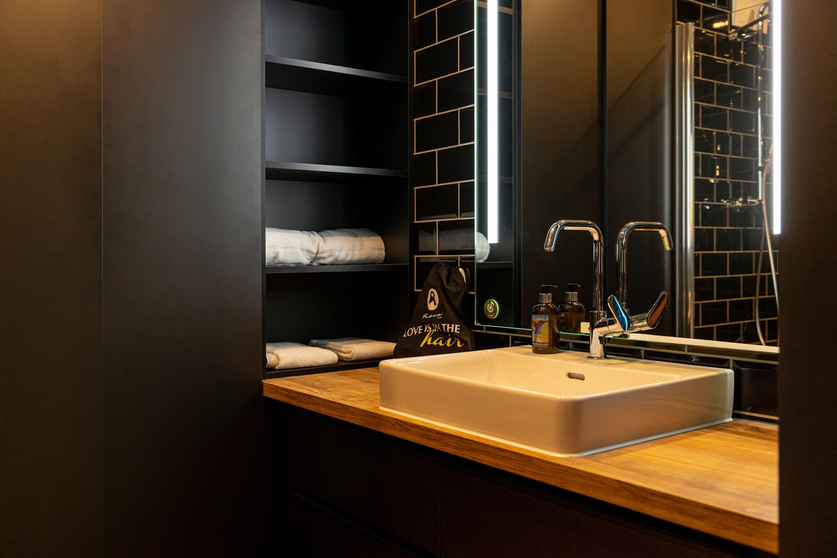 Un baño moderno con un espejo grande, un lavabo blanco y un mueble de tocador de madera.