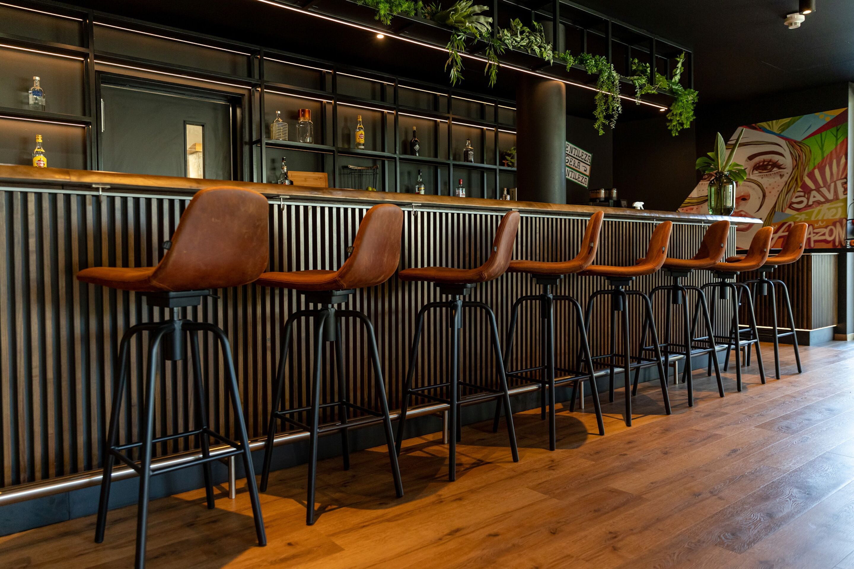 A bar area with wooden stools and a black metal bar counter.
