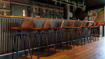 A bar area with wooden stools and a black metal bar counter.